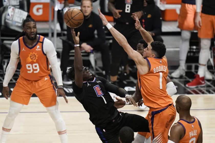 Los Angeles Clippers' Reggie Jackson, center left, is defended by Phoenix Suns' Devin Booker.