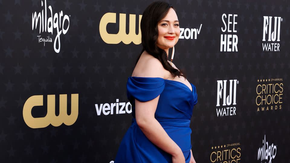 Lily Gladstone wore a deep blue satin dress by Christian Siriano, with her lipstick adding an extra pop of color. - Michael Tran/AFP/Getty Images