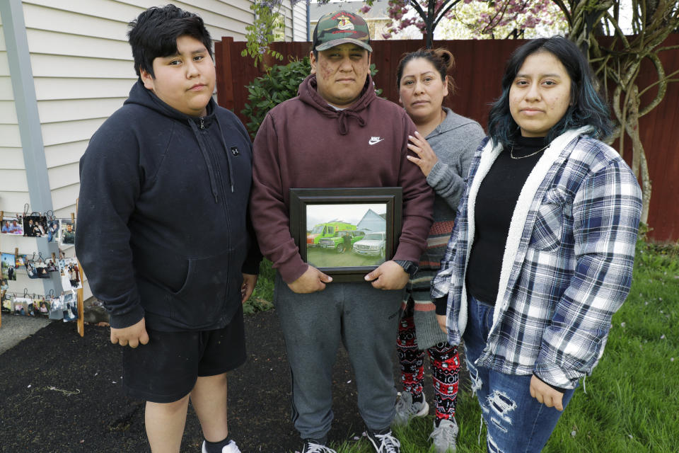 En esta foto del 23 de abril de 2020, Isaac López, de 19 años, segundo de la izquierda, sostiene una foto de su padre, Tomás López, al posar con su madre Antonia, segunda de la derecha; su hermano Elías, de 12 años; y su hermana Elda, de 16, en su casa en Pacific, Wash. Tomás, quien murió de COVID-19 el 2 de abril a los 44 años, era un apreciado vendedor de tacos. (AP Foto/Ted S. Warren)