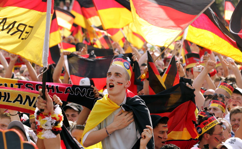 FILE - A German soccer fan sings the German national anthem prior to the beginning of the Round of 16 of the World Cup soccer match Germany against Sweden at the public viewing area where fans could watch the match live from Munich, on a giant television screen in Berlin, Saturday, June 24, 2006. Germany gets the 2024 European Championship underway against Scotland in Munich on Friday. However, away from the stadiums and public-viewing areas, few German flags are flying. Germany's dark history, rising far-right cast shadow on national pride before it hosts Euro 2024. (AP Photo/Franka Bruns, File)