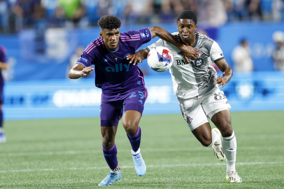 Charlotte FC defender Adilson Malanda, left, and Toronto FC forward Hugo Mbongue race to the ball during the first half of an MLS soccer match in Charlotte, N.C., Wednesday, Oct. 4, 2023. (AP Photo/Nell Redmond)