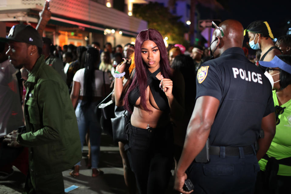 MIAMI BEACH, FLORIDA - MARCH 21: A Miami Beach police officer informs people of an 8pm curfew on March 21, 2021 in Miami Beach, Florida. College students have arrived in the South Florida area for the annual spring break ritual, prompting city officials to impose an 8pm to 6am curfew as the coronavirus pandemic continues. Miami Beach police have reported hundreds of arrests and stepped up deployment to control the growing spring break crowds. (Photo by Joe Raedle/Getty Images)