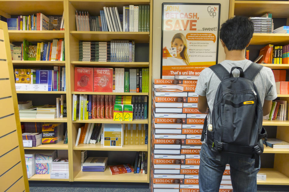 A student stands in from of books in a campus bookstore.