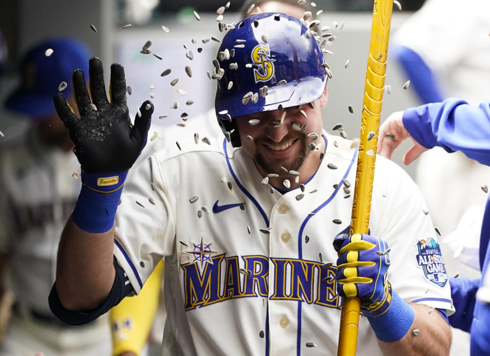 Seattle Mariners designated hitter Cal Raleigh holds a trident in the dugout after hitting a home run against the Pittsburgh Pirates as teammates throw sunflower seeds at him during the fourth inning of a baseball game Sunday, May 28, 2023, in Seattle. (AP Photo/Lindsey Wasson)