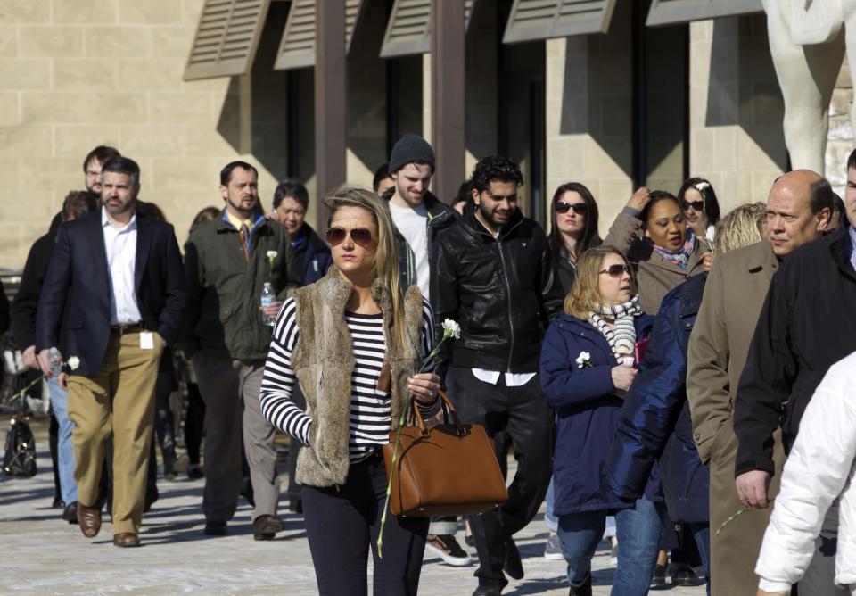 Columbia Mall employees holding carnations walk to the mall which is expected to open at 1;00 p.m., on Monday Jan. 27, 2014, in Howard County, Md. Three people died Saturday in a shooting at a mall in suburban Baltimore, including the presumed gunman. ( AP Photo/Jose Luis Magana)