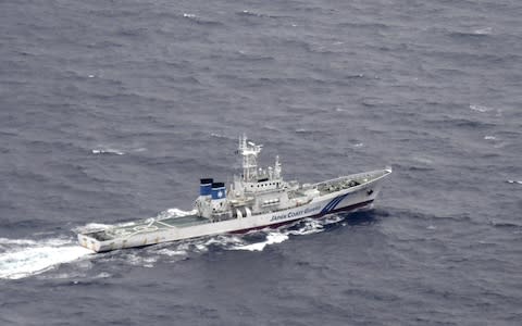 A Japan Coast Guard patrol vessel sails on the water at the area where two US Marine Corps aircraft are thought to have crashed - Credit: REUTERS