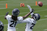 Seattle Seahawks cornerbacks Tre Flowers, left, and D.J. Reed, right, reach for the football during a drill at NFL football practice Tuesday, June 15, 2021, in Renton, Wash. (AP Photo/Ted S. Warren)