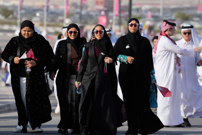 Mujeres con lentes de sol con los colores de la bandera de Qatar llegan al Estadio Al Bayt