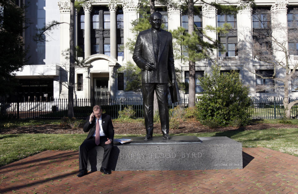 FILE - In this Saturday, March 13, 2010, file photo, House Majority Leader H. Morgan Griffith, R-Salem, talks on a phone as he sits at the feet of the statue of former governor and U.S. Sen. Harry F. Byrd at Capitol Square in Richmond, Va. Work is expected to begin Wednesday, July 7, 2021, to remove a statue of Harry F. Byrd Sr., a staunch segregationist, from the state’s Capitol Square. (Bob Brown/Richmond Times-Dispatch via AP, File)