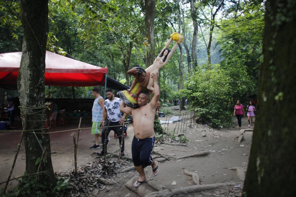 In this photo taken Oct. 13, 2019, a man carries a statue of indigenous goddess Maria Lionza riding on a tapir, on Sorte Mountain where her followers gather annually in Venezuela's Yaracuy state. According to legend, the goddess came from the mountain at Sorte, near the northwestern town of Chivacoa. (AP Photo/Ariana Cubillos)