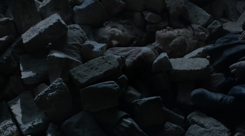 the siblings under a pile of rocks with their faces exposed
