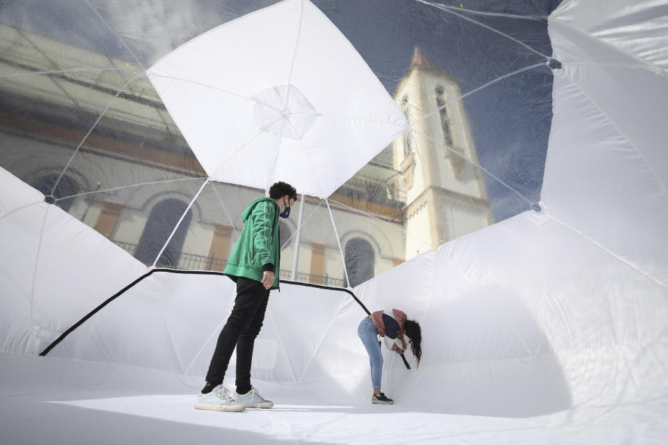 Designers stand inside a Portable Epidemiological Insulation Unit during a media presentation, in Bogota, Colombia, Tuesday, Feb. 16, 2021. Colombia’s La Salle University school of architecture designed the small polyhedral pneumatic geodesic domes which can be used to isolate and treat COVID-19 patients in areas where there are no nearby hospitals or where existing hospitals are overwhelmed with patients. (AP Photo/Fernando Vergara)