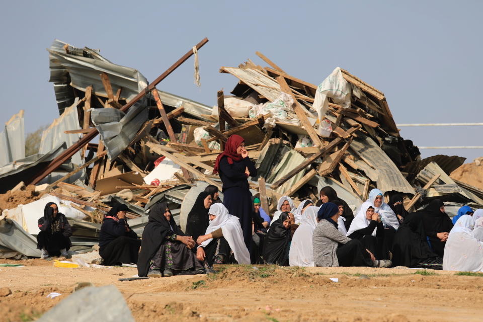 Bedouin women sit outside a demolished structure in the southern village of Umm al-Hiran, Wednesday, Jan. 18, 2017. Israeli police say an Israeli Arab rammed his vehicle into a group of police officers, killing one of them before he was shot dead during clashes in southern Israel over a court-ordered operation to demolish illegally built homes. Local residents say police used excessive force to remove protesters, including live fire, and Amnesty International called for a probe into reports of police brutality. (AP Photo/Tsafrir Abayov)