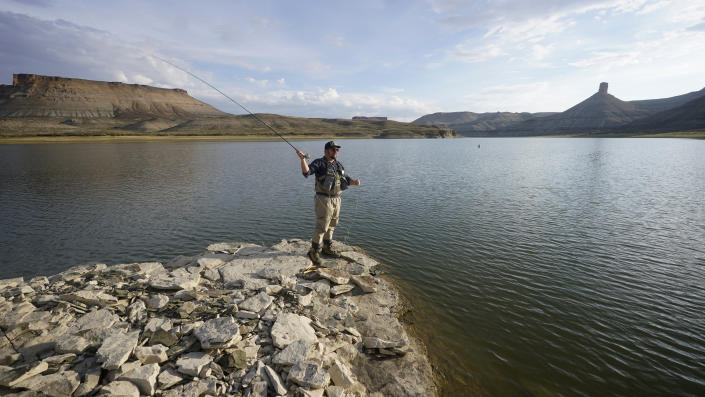 Nick Gann fishes Friday, Aug. 5, 2022, on the far northeastern shore of Flaming Gorge Reservoir, in Wyoming. A boating and fishing paradise on the Utah-Wyoming line, Flaming Gorge is beginning to feel the effects of the two-decade megadrought gripping the southwestern U.S. (AP Photo/Rick Bowmer)