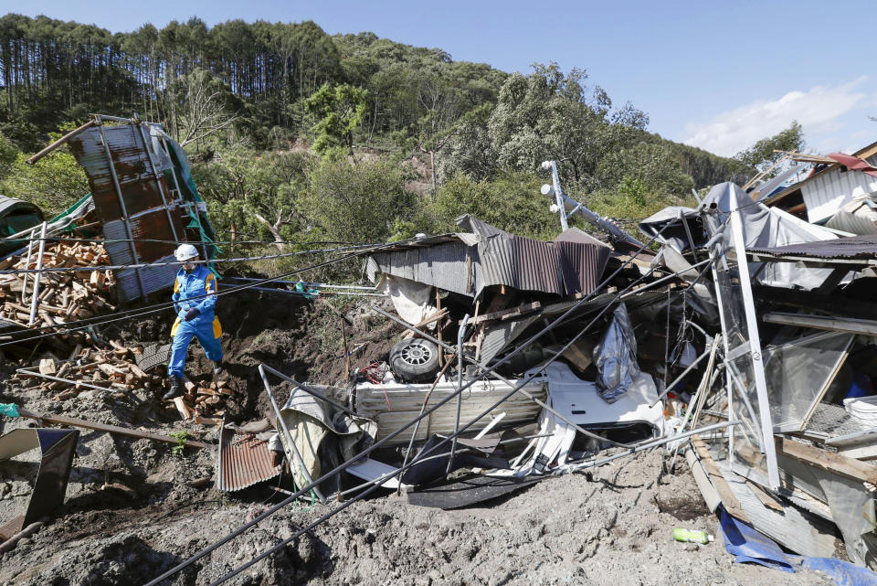 A police officer checks around buildings destroyed by a landslide after a powerful earthquake in Atsuma town, Hokkaido, northern Japan, Thursday, Sept. 6, 2018. Several people were reported missing in the nearby the town, where a massive landslide engulfed homes in an avalanche of soil, rocks and timber. (Masanori Takei/Kyodo News via AP)