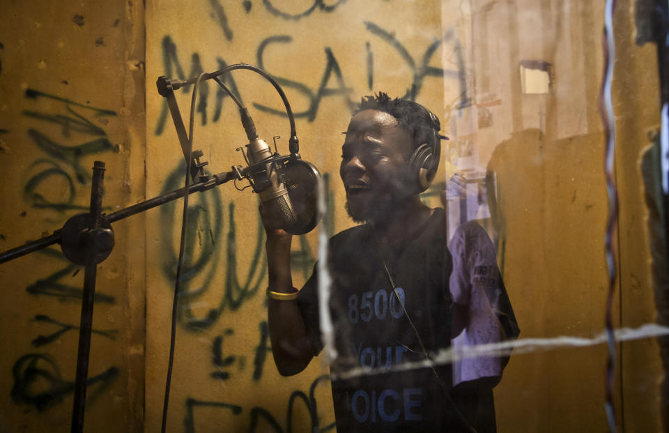 FILE - In this Wednesday, Nov. 5, 2014 file photo, Hood Katende, a 26-year-old reformed thief and onetime drug peddler who now produces music encouraging AIDS awareness, performs in a small shipping container-turned recording studio in the Kamwokya slum of Kampala, Uganda. In 2019 fewer people in many parts of sub-Saharan Africa are dying of AIDS as treatment becomes more widely available, yet some officials worry that success may be encouraging a sense of complacency. (AP Photo/Rebecca Vassie, File)