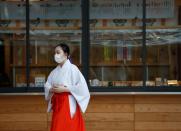 A Shinto maiden wearing a protective face mask walks amid the coronavirus disease (COVID-19) outbreak, in Tokyo