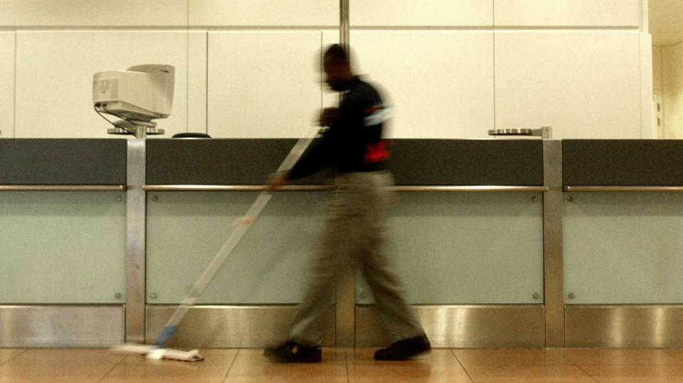 A janitor sweeps up at an airport.