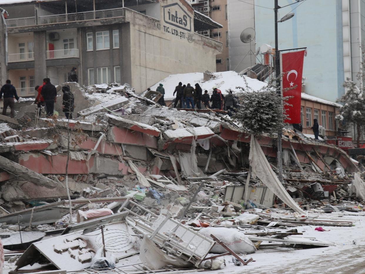 Rescuers carry a person from the ruins of a collapsed building, lightly covered in snow, in Malatya, Turkey, following the earthquake on February 6, 2023