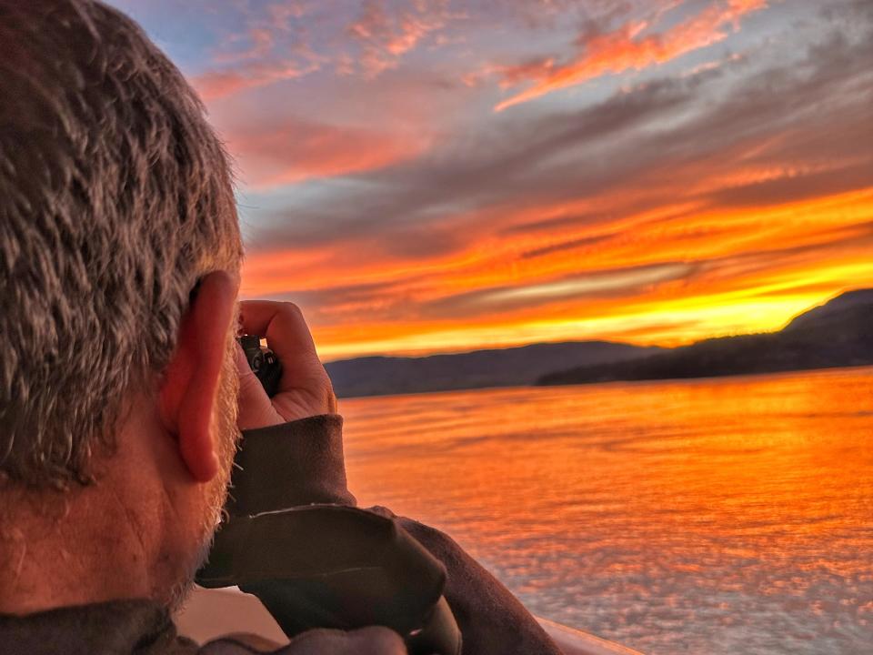 Man taking photo of sunset on boat