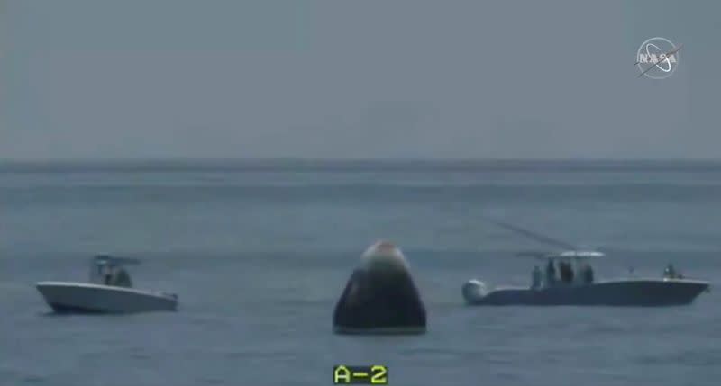 Recovery teams approach a capsule with NASA astronauts Robert Behnken and Douglas Hurley which splashed down in the Gulf of Mexico