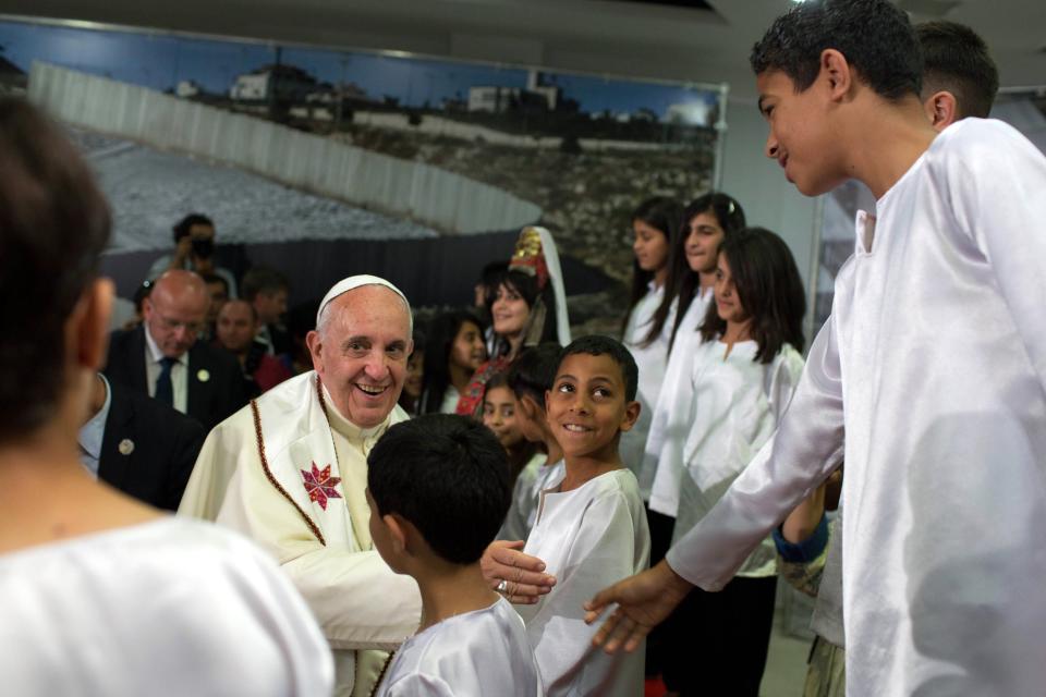 Pope Francis shakes hands with a boy during a visit to the Dheisheh refugee camp on outskirts of Bethlehem