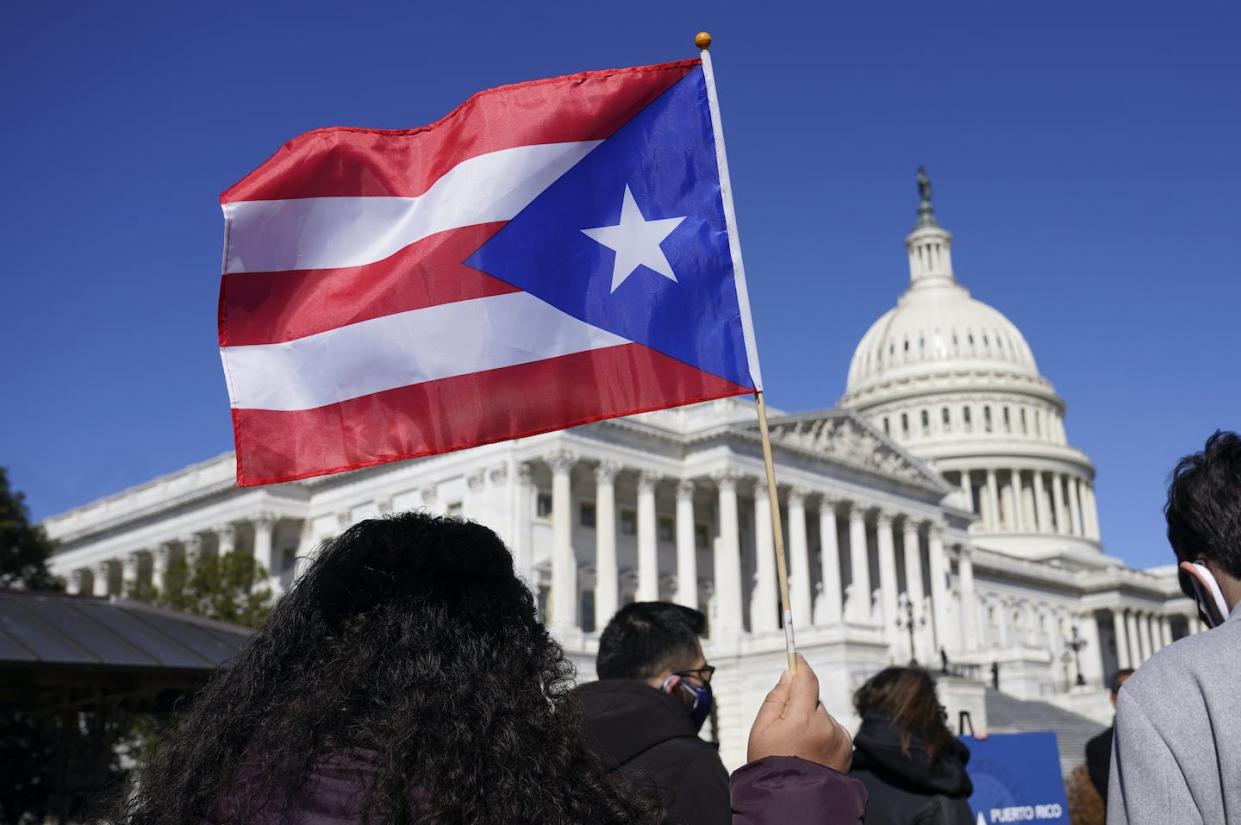 A woman waves a Puerto Rico flag to support Puerto Rican statehood on March 2, 2021. <a href="https://newsroom.ap.org/detail/USPuertoRicoEconomy/d35bbadd375f4f5b92e41094d5fdd7b5" rel="nofollow noopener" target="_blank" data-ylk="slk:AP Photo/Patrick Semansky;elm:context_link;itc:0;sec:content-canvas" class="link ">AP Photo/Patrick Semansky</a>