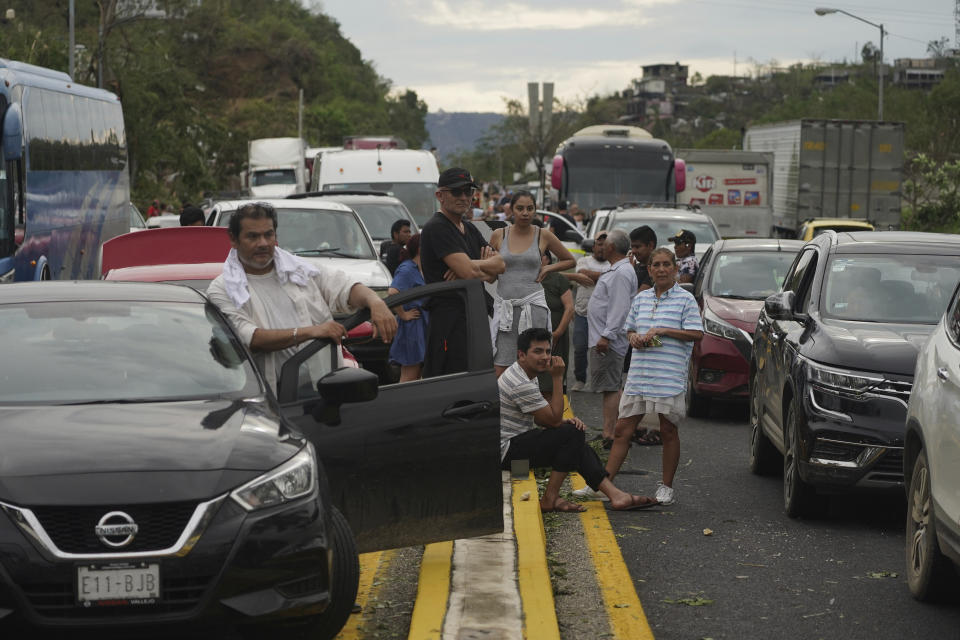 People wait outside their cars as they wait for repair crews to unclog the roads after Hurricane Otis ripped through Acapulco, Mexico, Wednesday, Oct. 25, 2023. Hurricane Otis ripped through Mexico's southern Pacific coast as a powerful Category 5 storm, unleashing massive flooding, ravaging roads and leaving large swaths of the southwestern state of Guerrero without power or cellphone service. (AP Photo/Marco Ugarte)