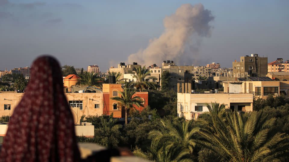 A Palestinian woman watches as smoke billows following an Israeli strike south of Gaza City. - Eyad Baba/AFP/Getty Images