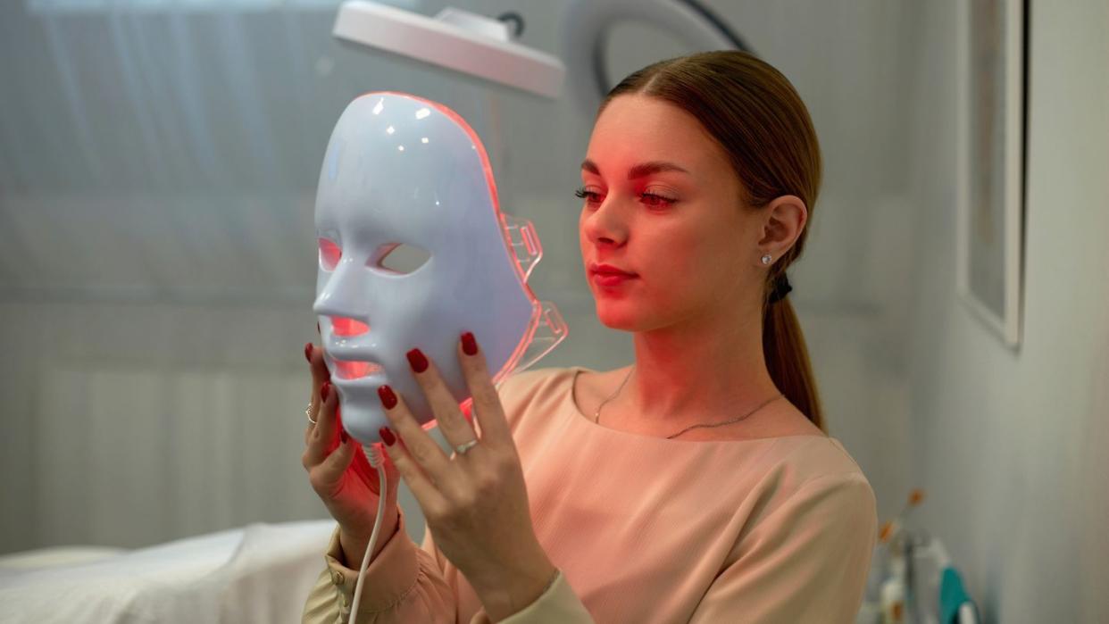 woman holding light therapy mask