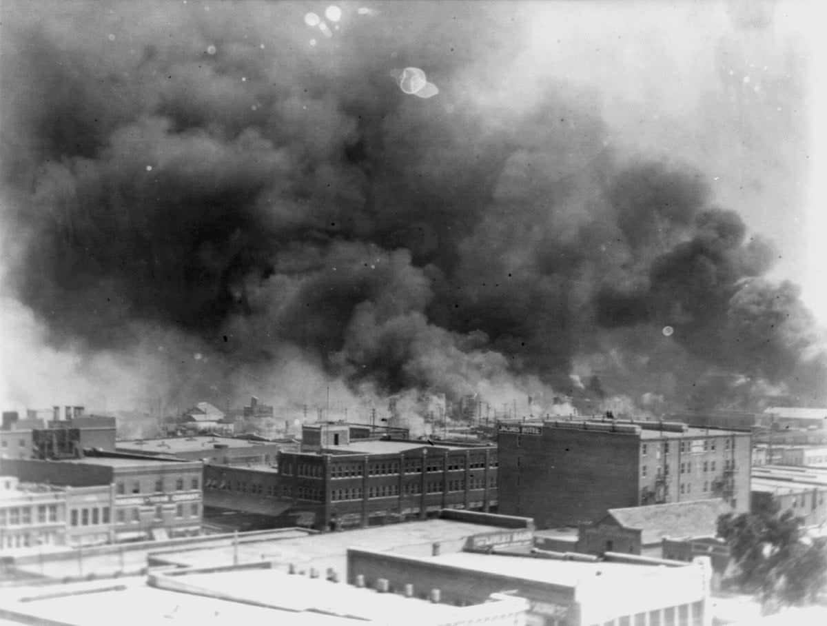 Smoke billows above Tulsa during a racist massacre in 1921 (AP)