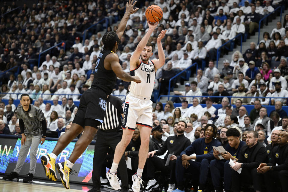 UConn forward Alex Karaban shoots over Marquette guard Chase Ross, left, in the first half of an NCAA college basketball game, Saturday, Feb. 17, 2024, in Hartford, Conn. (AP Photo/Jessica Hill)