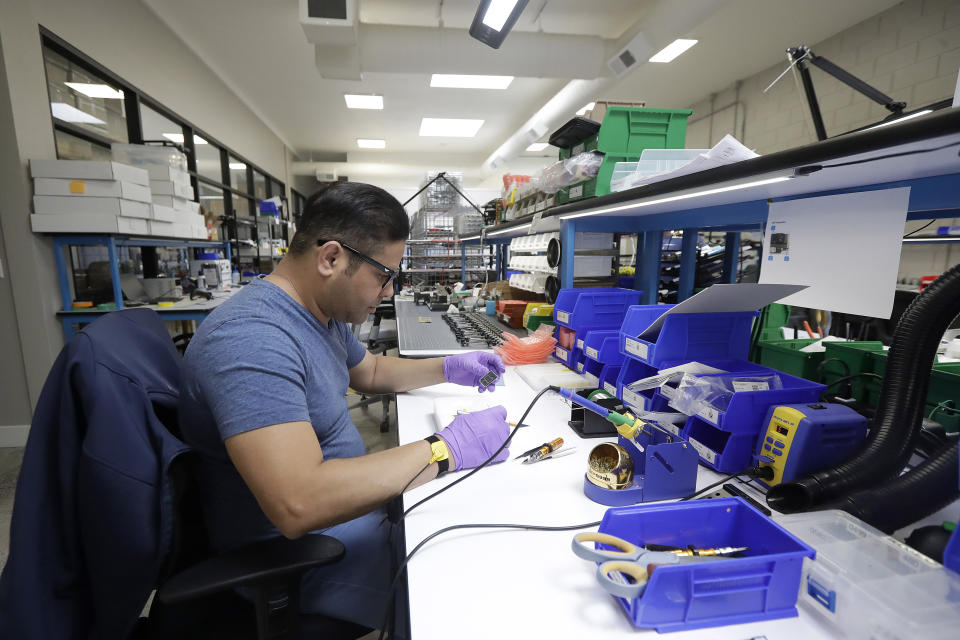 In this June 22, 2018, photo, Skydio tech assembler Alex Nakmoto works on the R1 flying camera drones in a laboratory in Redwood City, Calif. Skateboarders, surfers and YouTube stars used to be the target customers for California drone startup Skydio, which builds sophisticated self-flying machines that can follow people around and capture their best moves on video. Now it's police officers and soldiers getting equipped with the pricey drones. U.S. political and security concerns about the world's dominant consumer drone-maker, China-based DJI, have opened the door for Skydio and other companies to pitch their drones for government and business customers. (AP Photo/Jeff Chiu)