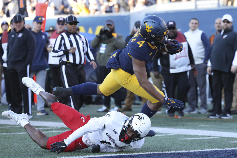 West Virginia's C.J. Donaldson (4) dives into the end zone for a rushing touchdown over Cincinnati's Jordan Young (1) during the first half of an NCAA college football game, Saturday, Nov. 18, 2023, in Morgantown, W.Va. (AP Photo/Chris Jackson)