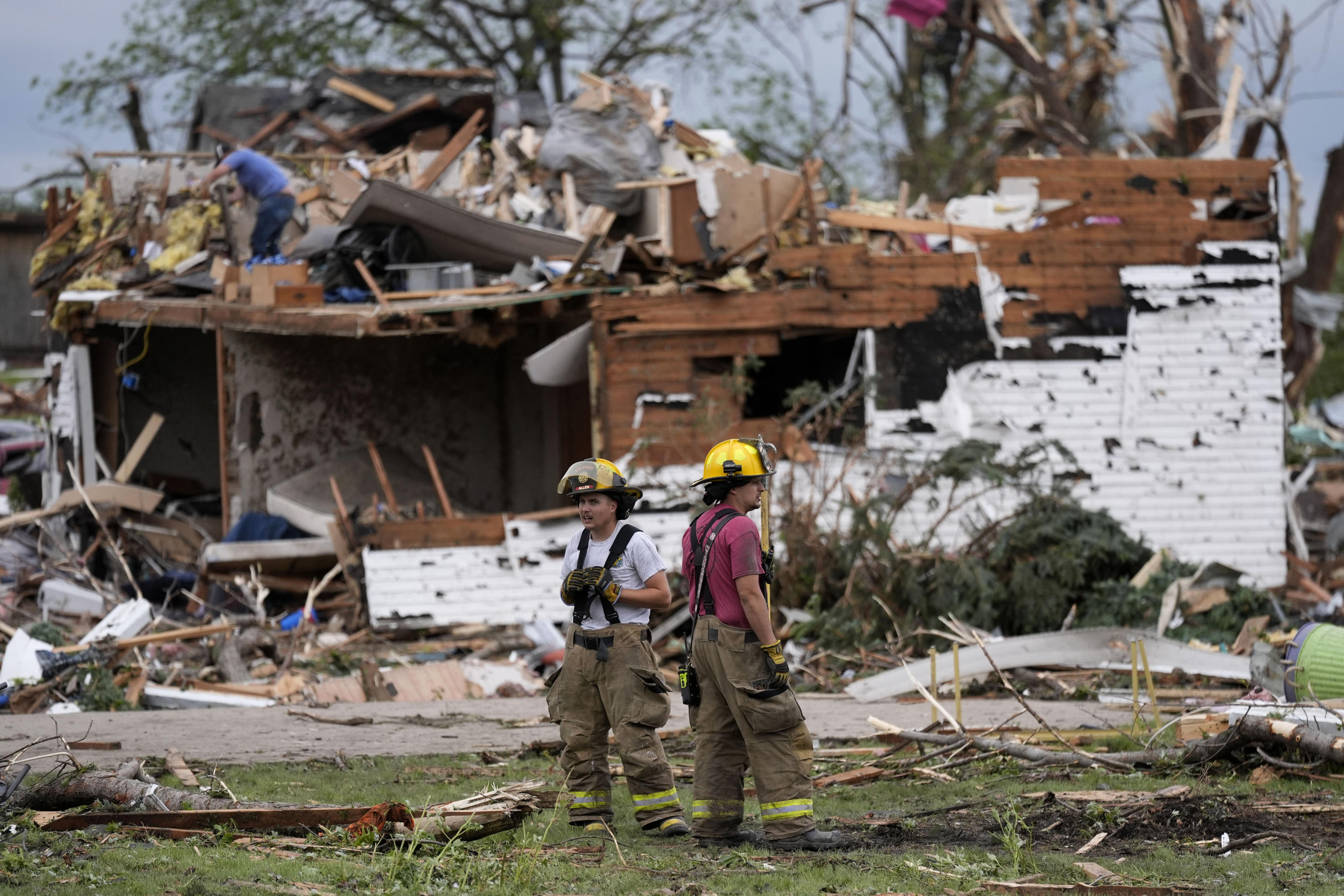 Firefighters stand among the remains of homes destroyed by a tornado on Tuesday in Greenfield, Iowa.