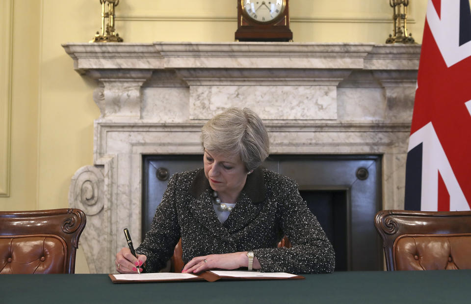 Britain's Prime Minister Theresa May signs the official letter to European Council President Donald Tusk, in 10 Downing Street, London, Tuesday March 28, 2017, invoking Article 50 of the bloc's key treaty, the formal start of exit negotiations. Britons voted in June to leave the bloc after four decades of membership. (Christopher Furlong/Pool Photo via AP)