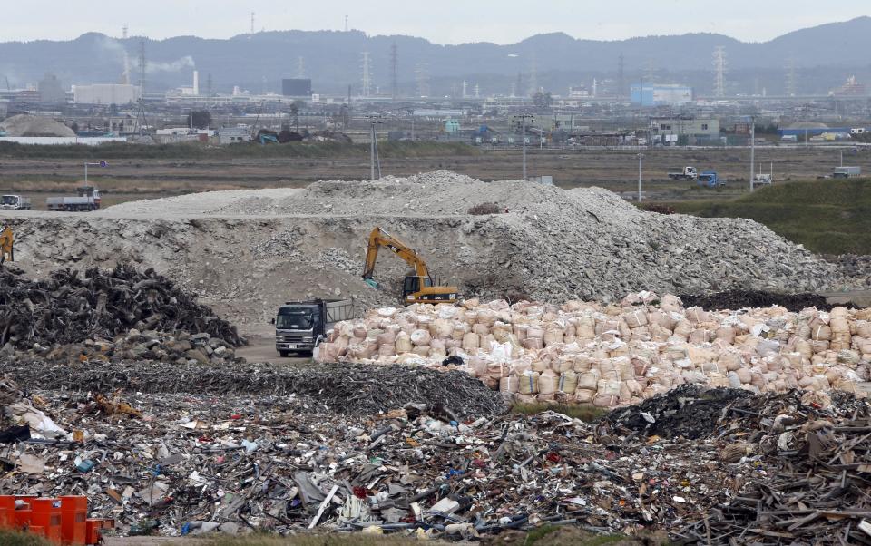 In this Oct. 10, 2012 photo, a yellow crane sorts out the rubble of the March 11, 2011 earthquake and tsunami, at the rubble collection site near the Arahama beach in Sendai, northeastern Japan. Japan's accounting of its budget for reconstruction from the disasters is crammed with spending on unrelated projects, while all along Japan's northeastern coast, dozens of communities remain uncertain of whether, when and how they will rebuild. (AP Photo/Koji Sasahara)