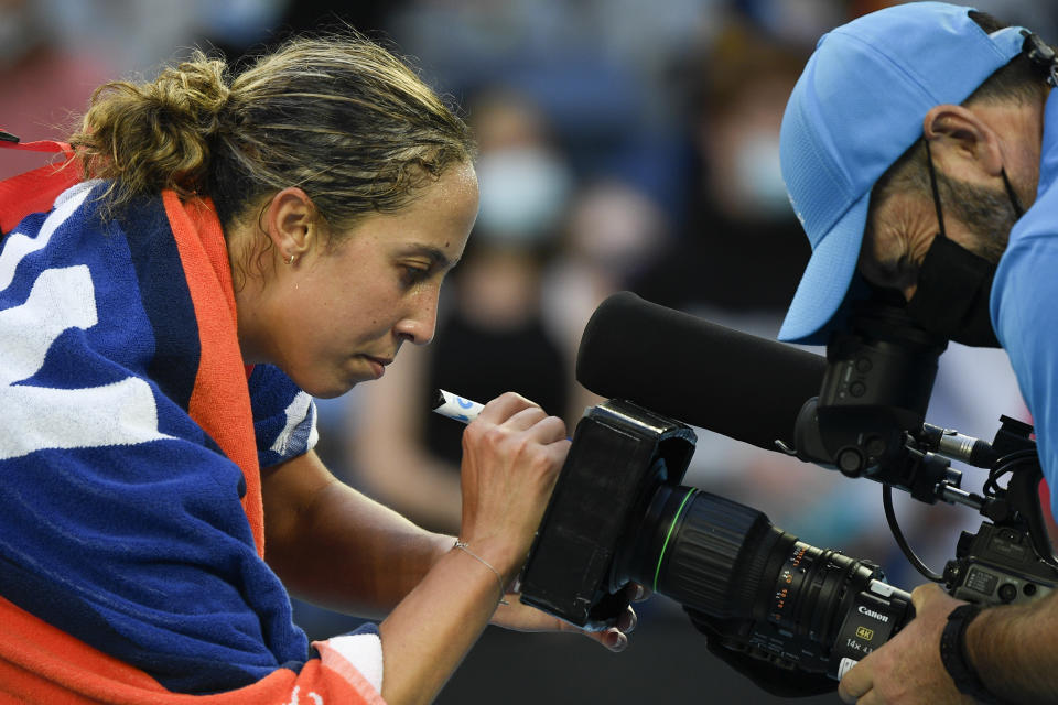 Madison Keys of the U.S. autographs a tv camera after defeating compatriot Sofia Kenin in their first round match at the Australian Open tennis championships in Melbourne, Australia, Monday, Jan. 17, 2022. (AP Photo/Andy Brownbill)