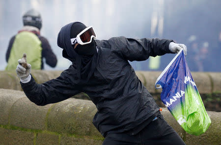 A masked protester throws a projectile towards police during a demonstration of the "yellow vests" movement in Nantes, France, January 26, 2019. REUTERS/Stephane Mahe