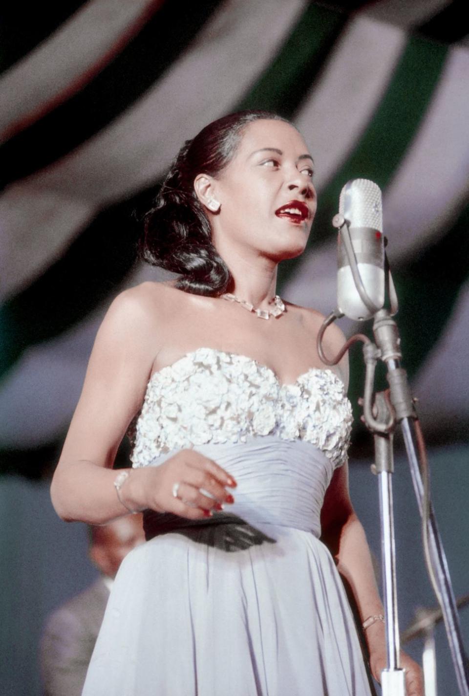 <p>Music legend Billie Holiday performing in a strapless powder-blue gown with an embellished bodice and a bright-red lip.</p>