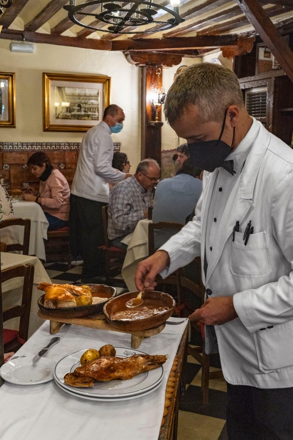 A waiter serving food at a table.