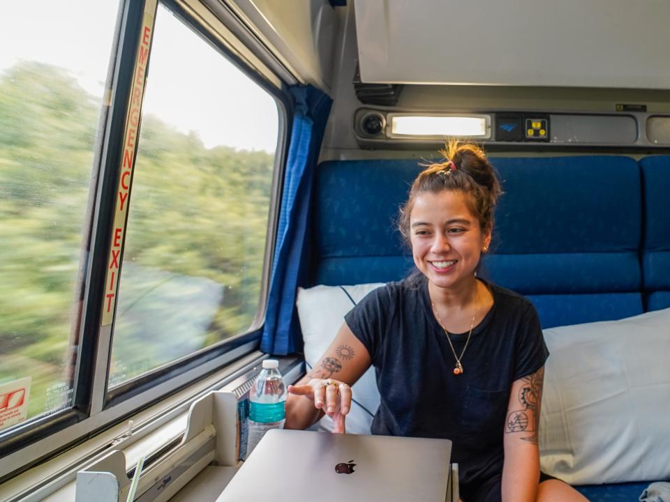 The author sits in the blue seat and closes her laptop while smiling