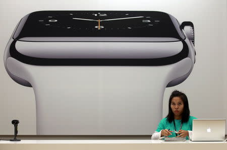 A sales assistant works in front of an advertisement for the Apple watch at an Apple reseller shop in Bangkok, Thailand, in this July 17, 2015 file photo.REUTERS/Chaiwat Subprasom/Files