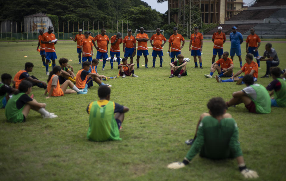 Coaches speak to youths during a break of a soccer training session at the Pedro Marrero stadium in Havana, Cuba, Wednesday, Sept. 14, 2022. These coaches also will be responsible for training more than 1,500 other coaches across the island in upcoming months. (AP Photo/Ramon Espinosa)
