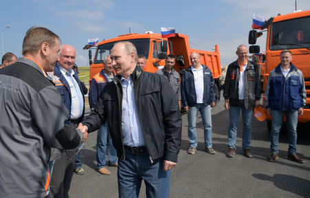 Russian President Vladimir Putin (R, front) greets builders before a ceremony opening a bridge, which was constructed to connect the Russian mainland with the Crimean Peninsula, near the Taman Peninsula in Krasnodar Region, Russia May 15, 2018. Sputnik/Alexei Druzhinin/Kremlin via REUTERS