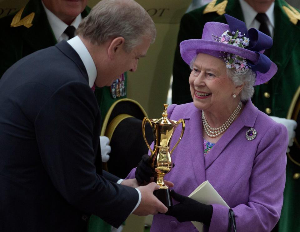 Prince Andrew, the Duke of York, presents his mother, Queen Elizabeth II, with a trophy after her horse Estimate won the Gold Cup at Royal Ascot in June 2013.