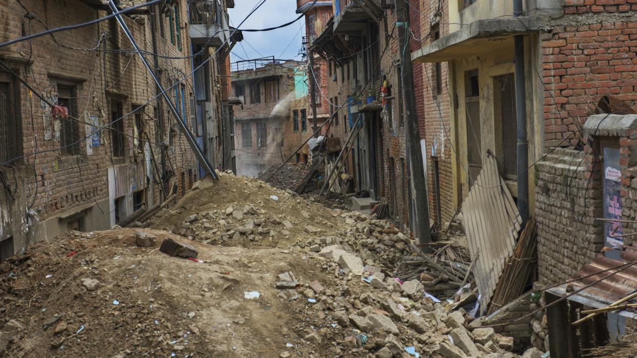 Khokana village in Kathmandu, Nepal, after a damaging earthquake. Here we see a narrow street filled with rubble and lined with damaged buildings and electrical wires. 
