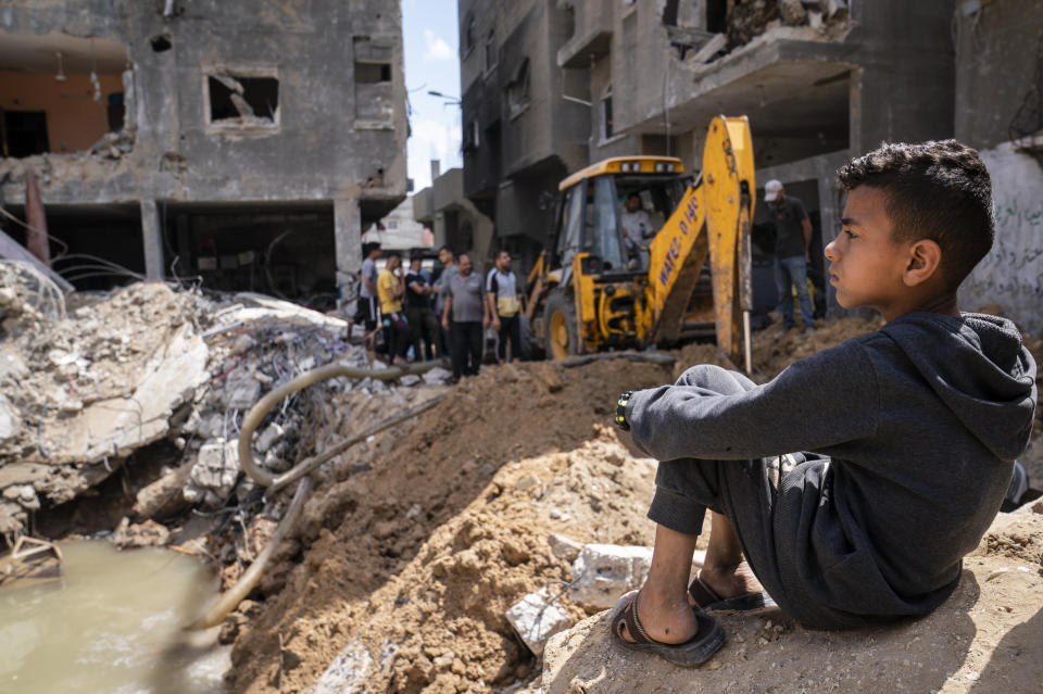 Children gather beside the crater where the home of Ramez al-Masri was destroyed by an air-strike prior to a cease-fire reached after an 11-day war between Gaza's Hamas rulers and Israel, Sunday, May 23, 2021, in Beit Hanoun, the northern Gaza Strip. (AP Photo/John Minchillo)