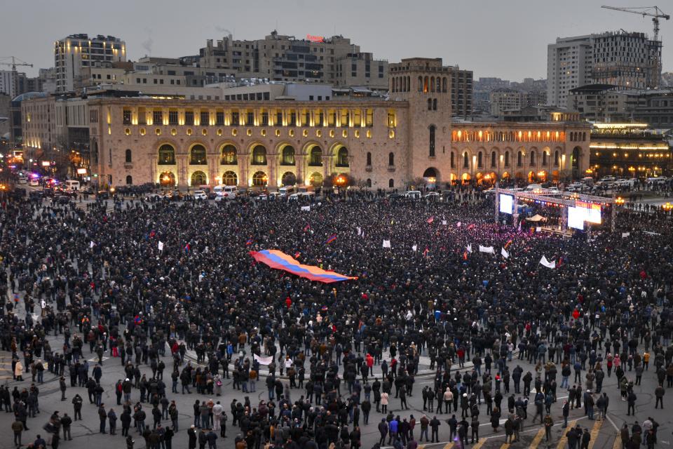 Supporters of Armenian Prime Minister Nikol Pashinyan gather with an Armenian national flag during a rally in his support in the center of Yerevan, Armenia, Monday, March 1, 2021. Amid escalating political tensions in Armenia, supporters of the country's embattled prime minister and the opposition are staging massive rival rallies in the capital of Yerevan. Prime Minister Nikol Pashinyan has faced opposition demands to resign since he signed a peace deal in November that ended six weeks of intense fighting with Azerbaijan over the Nagorno-Karabakh region. (Karo Sahakyan/PAN Photo via AP)