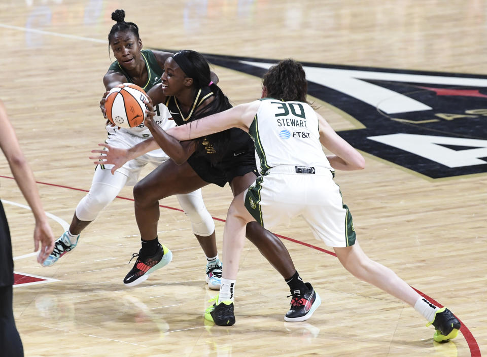 Las Vegas Aces guard Jackie Young, center, cuts between Seattle Storm guard Jewell Loyd, left, and forward Breanna Stewart (30) during the first half of a WNBA basketball game Sunday, Aug. 14, 2022, in Las Vegas. (AP Photo/Sam Morris)